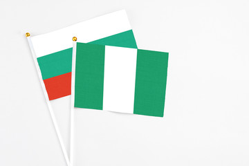 Nigeria and Bulgaria stick flags on white background. High quality fabric, miniature national flag. Peaceful global concept.White floor for copy space.