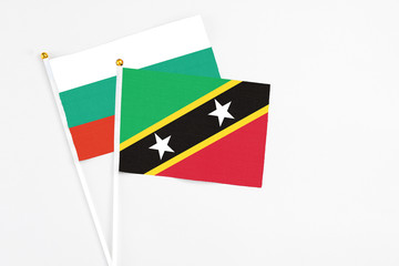 Saint Kitts And Nevis and Bulgaria stick flags on white background. High quality fabric, miniature national flag. Peaceful global concept.White floor for copy space.