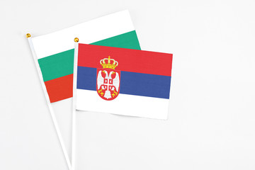 Serbia and Bulgaria stick flags on white background. High quality fabric, miniature national flag. Peaceful global concept.White floor for copy space.