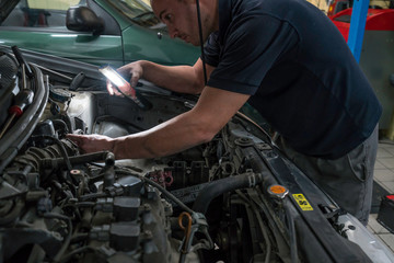 Fototapeta na wymiar Auto mechanic working on car engine in mechanics garage. Car repair service.