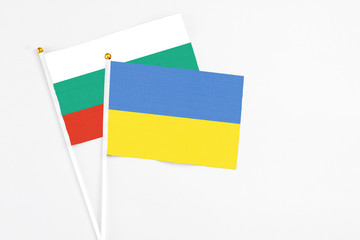 Ukraine and Bulgaria stick flags on white background. High quality fabric, miniature national flag. Peaceful global concept.White floor for copy space.