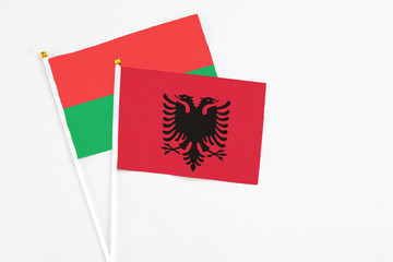 Albania and Burkina Faso stick flags on white background. High quality fabric, miniature national flag. Peaceful global concept.White floor for copy space.