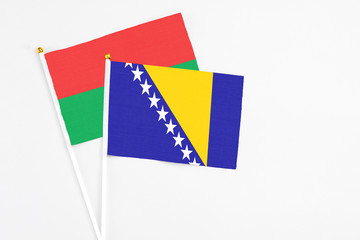 Bosnia Herzegovina and Burkina Faso stick flags on white background. High quality fabric, miniature national flag. Peaceful global concept.White floor for copy space.