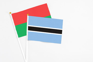 Botswana and Burkina Faso stick flags on white background. High quality fabric, miniature national flag. Peaceful global concept.White floor for copy space.