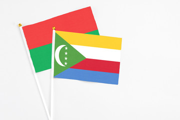 Comoros and Burkina Faso stick flags on white background. High quality fabric, miniature national flag. Peaceful global concept.White floor for copy space.