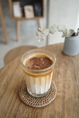 Iced coffee latte with brown upper layer coffee and white lower layer fresh milk in glass on wooden table