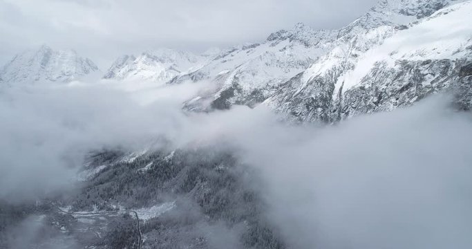 Aerial above view of winter Siguniangshan National Park with clouds floating in the air above the pine tree forest valley snow mountain summit winter nature mountain landscape Travel Extreme Heights  