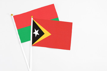 East Timor and Burkina Faso stick flags on white background. High quality fabric, miniature national flag. Peaceful global concept.White floor for copy space.