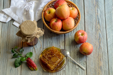 The jar with honey and apples in a wicker basket close-up