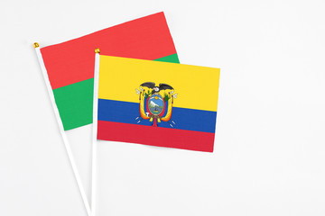 Fototapeta premium Ecuador and Burkina Faso stick flags on white background. High quality fabric, miniature national flag. Peaceful global concept.White floor for copy space.