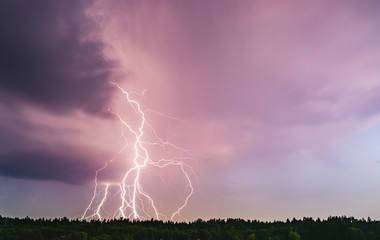 Dramatic lightning bolt at night over rural area. Agriculture fields.