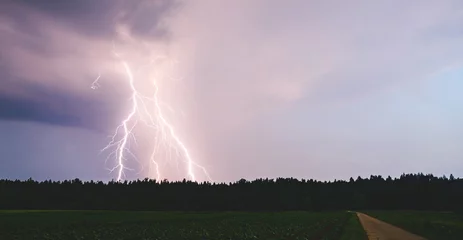 Fotobehang Dramatic lightning bolt at night over rural area. Agriculture fields. © Przemyslaw Iciak
