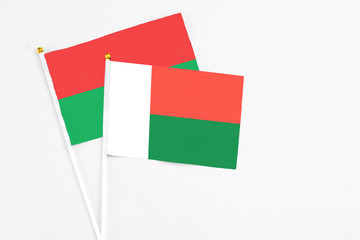 Madagascar and Burkina Faso stick flags on white background. High quality fabric, miniature national flag. Peaceful global concept.White floor for copy space.