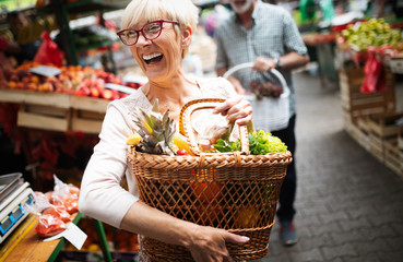 Picture of mature woman at marketplace buying vegetables