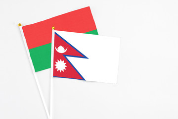 Nepal and Burkina Faso stick flags on white background. High quality fabric, miniature national flag. Peaceful global concept.White floor for copy space.