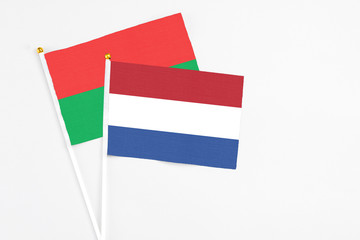Netherlands and Burkina Faso stick flags on white background. High quality fabric, miniature national flag. Peaceful global concept.White floor for copy space.