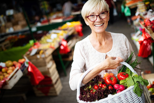 Mature Woman Buying Vegetables At Farmers Market