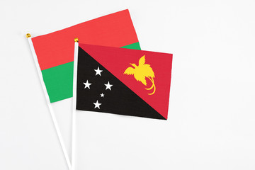 Papua New Guinea and Burkina Faso stick flags on white background. High quality fabric, miniature national flag. Peaceful global concept.White floor for copy space.