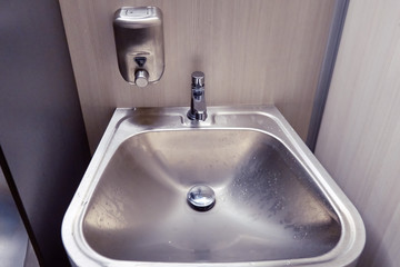 New modern metal sink with soap dispenser in public toilet