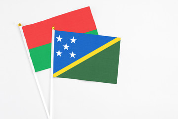 Solomon Islands and Burkina Faso stick flags on white background. High quality fabric, miniature national flag. Peaceful global concept.White floor for copy space.