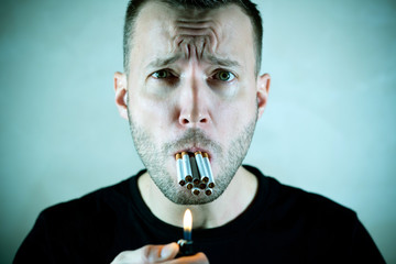 a man with a suffering face holds a lot of cigarettes in his mouth and looks at the camera