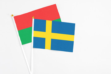 Sweden and Burkina Faso stick flags on white background. High quality fabric, miniature national flag. Peaceful global concept.White floor for copy space.