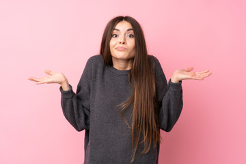 Young woman over isolated pink background having doubts while raising hands