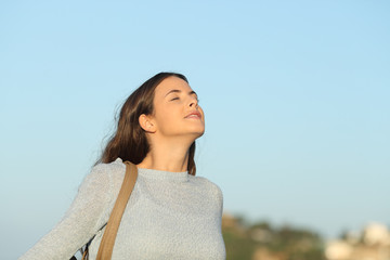 Relaxed woman breathing fresh air with a blue sky