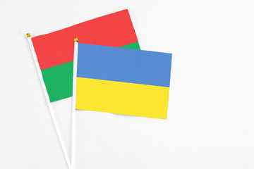 Ukraine and Burkina Faso stick flags on white background. High quality fabric, miniature national flag. Peaceful global concept.White floor for copy space.