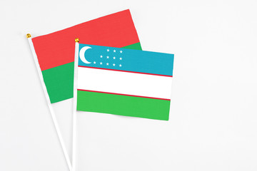 Uzbekistan and Burkina Faso stick flags on white background. High quality fabric, miniature national flag. Peaceful global concept.White floor for copy space.