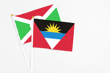 Antigua and Barbuda and Burundi stick flags on white background. High quality fabric, miniature national flag. Peaceful global concept.White floor for copy space.