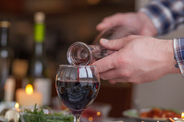 Close up of unrecognizable person pouring wine from a decanter.