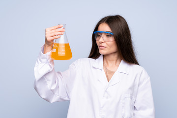 Young woman over isolated blue background with a scientific test tube