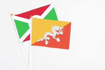 Bhutan and Burundi stick flags on white background. High quality fabric, miniature national flag. Peaceful global concept.White floor for copy space.