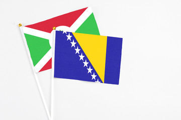 Bosnia Herzegovina and Burundi stick flags on white background. High quality fabric, miniature national flag. Peaceful global concept.White floor for copy space.