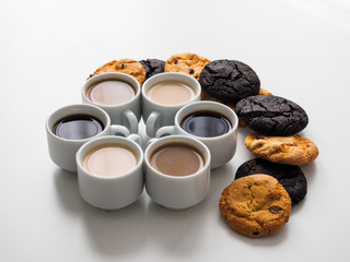 Coffee of different colors in cups exposed circle in the form of snowflakes. Lots of different cookies