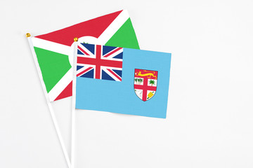 Fototapeta premium Fiji and Burundi stick flags on white background. High quality fabric, miniature national flag. Peaceful global concept.White floor for copy space.