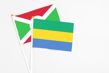 Gabon and Burundi stick flags on white background. High quality fabric, miniature national flag. Peaceful global concept.White floor for copy space.