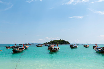 Naklejka na ściany i meble Koh Lipe, Andaman sea, Thailand. Beautiful Island of Koh Lipe, Long-tailed boat parking during Sunrise and Sunset by the beach. Beautiful white beach, blue sea with long tail boats in summer.