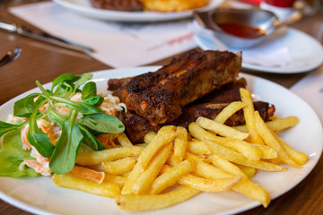 Barbecue pork spare ribs with fries. Grilled Barbecue spare ribs St Louis cut with hot honey chili marinade sliced. Selective focus of pork rip barbecue cooking meat with a grilled with fries.