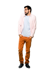 Naklejka premium Full-length shot of Handsome man with beard making doubts gesture looking side over isolated white background