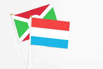 Luxembourg and Burundi stick flags on white background. High quality fabric, miniature national flag. Peaceful global concept.White floor for copy space.