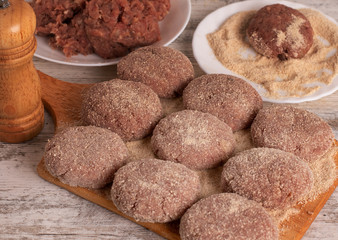 Homemade raw chopped meatball ready to cook. Cutlets in breadcrumbs lie on a cutting board