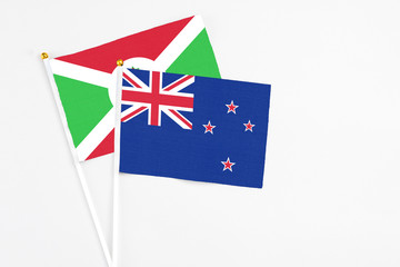 Fototapeta premium New Zealand and Burundi stick flags on white background. High quality fabric, miniature national flag. Peaceful global concept.White floor for copy space.