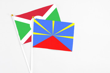Reunion and Burundi stick flags on white background. High quality fabric, miniature national flag. Peaceful global concept.White floor for copy space.