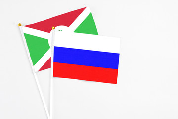 Russia and Burundi stick flags on white background. High quality fabric, miniature national flag. Peaceful global concept.White floor for copy space.