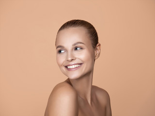 Portrait of beautiful young woman isolated on brown studio background. Caucasian female model looking and smiling. Concept of women's health and beauty, self-care, body, skin care, treatment.