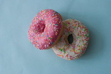 Delicious doughnuts with sprinkles on color background