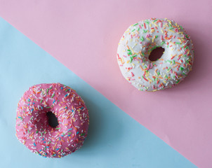 Delicious doughnuts with sprinkles on color background