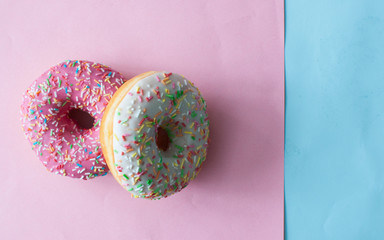 Delicious doughnuts with sprinkles on color background